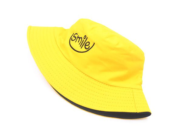 Frente del sombrero de cubo amarillo reversible con un logo de sonrisa